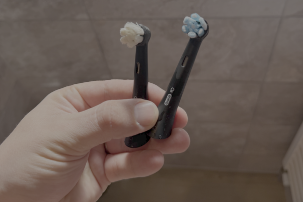 Two toothbrush heads side by side. One looks old, white, the other is brand new, with blue dye on the bristles.